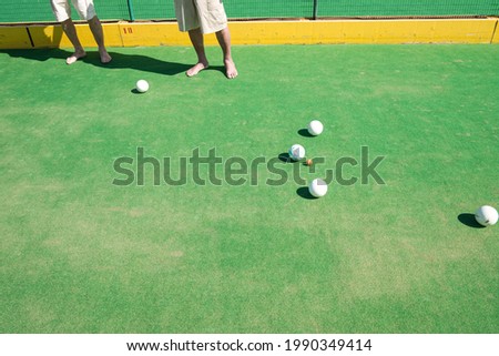 Barefoot people playing lawn bowls together, leisure and summer concept