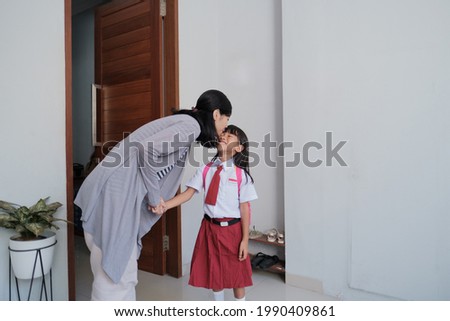 portrait of happy mother kiss her kid cheek in the morning at home before school day