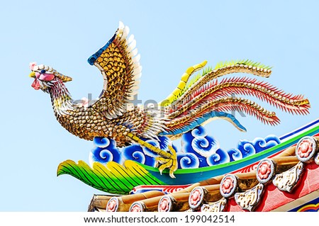 Chinese  phoenix statue on roof with blue sky.