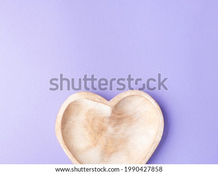 Empty heart shaped wooden dish on purple background. Flat lay
