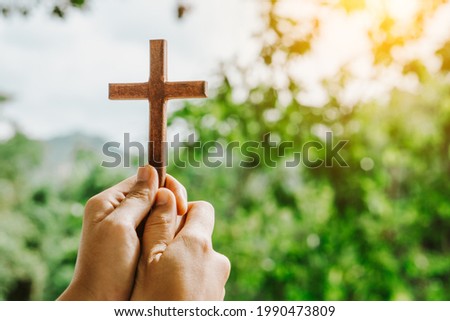 man praying with cross in nature sunrise background, Symbol of Faith. 