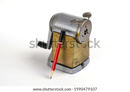 Wooden pencil and vintage sharpener on white background. Manual metal tool for sharpening wooden pencils. Selective focus.