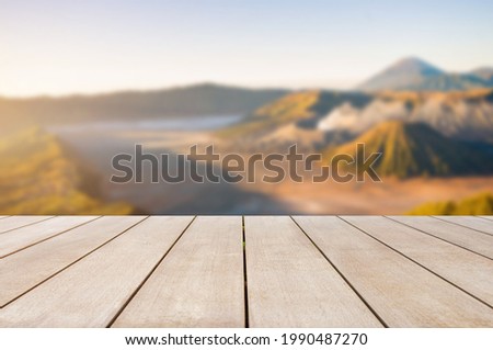 Empty old wooden table top in front of blurred view of mountains, foggy landscape, sky, tree, forest and sunlight background. Can be used for display or montage for show your products.