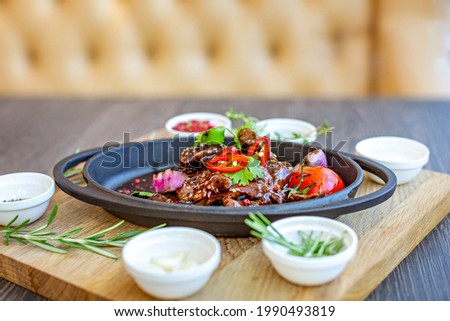 Roast meat with baked tomatoes and onions with sweet sauce, beautifully served in cast-iron dishes. Restaurant menu