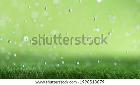 Freeze motion of rain drops falling on grass texture, studio shot, artificial lawn.