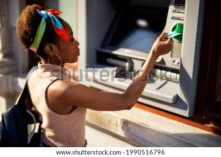  Beautiful african womn using ATM machine. Attractive young woman withdrawing money from credit card at ATM.