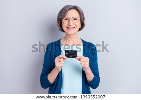 Photo of charming attractive positive old woman hold hands credit card good mood isolated on grey color background