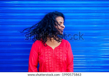 Attractive beautiful happy young latin hispanic woman with teak bindi on forehead smiling on blue wall street background