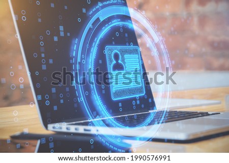 Close up of desktop with laptop and abstract glowing digital profile on blurry office background. ID and digital transformation concept. Double exposure Royalty-Free Stock Photo #1990576991