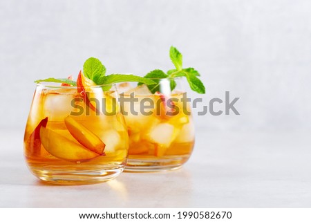 iced carbonated tea with peaches and mint in a glass on a gray background, horizontal, space for text Royalty-Free Stock Photo #1990582670