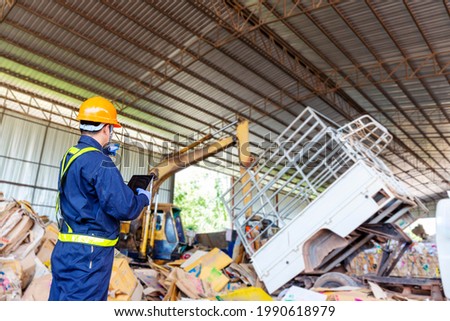 Engineer pointing forward. Engineer driving a loader in the recycling plant. Royalty-Free Stock Photo #1990618979