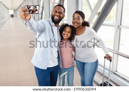Selfie At Airport. Young African American Family Of Three Taking Self Picture With Smartphone In Airport Terminal, Hugging And Posing At Camera, Traveling Together, Selective Focus