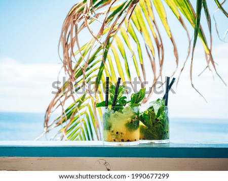 A relax time with two glasses of cold mojito cocktail put on a blue table on the beach