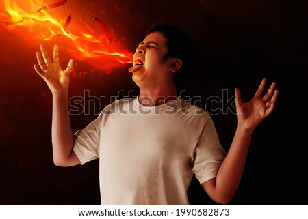 Portrait of young man eating chili pepper Royalty-Free Stock Photo #1990682873