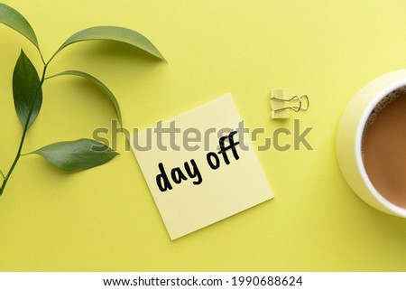 Paper sheet with text DAY OFF and cup of coffee on color background