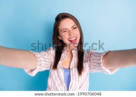 Photo of charming cheerful lady make selfie eye wink show tongue out isolated on blue color background
