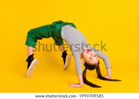 Full body profile side photo of young girl happy positive smile aerobics stand bridge pose isolated over yellow color background
