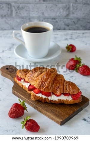 Croissant with cream cheese and strawberries for breakfast with a cup of coffee. Royalty-Free Stock Photo #1990709969