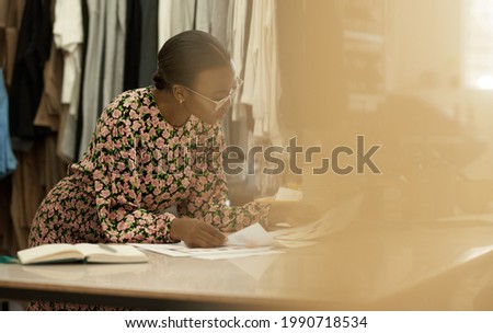 African female clothing designer looking at color samples in her studio