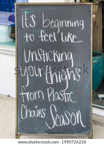 Quirky handwritten chalkboard sign outside a furniture shop on a barrier island along the Gulf Coast of Florida near the start of summer, for motifs of weather and humidity, seasons, activity
