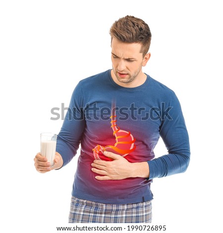 Young man with glass of milk suffering from heartburn on white background Royalty-Free Stock Photo #1990726895