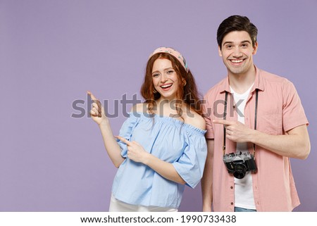 Two fun traveler tourist woman man couple in summer clothes point index finger aside on workspace isolated on purple background Passenger travel abroad on weekends getaway Air flight journey concept