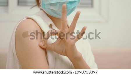 Teenager wearing protective mask against covid-19 with a smile on his face shows the vaccine brand, backgroundHealthy asian woman getting vaccinated immunity giving ok hand sign to rolling out vaccine Royalty-Free Stock Photo #1990753397