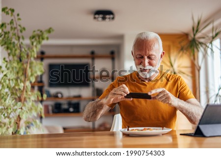Mature man, taking a picture of his meal, while getting ready to eat.