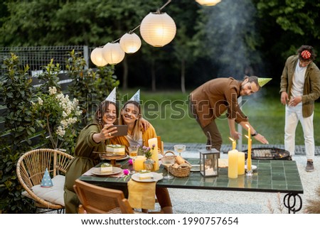 Friends having great summertime on a backyard of a country house. Celebrating birthday and having festive dinner in nature