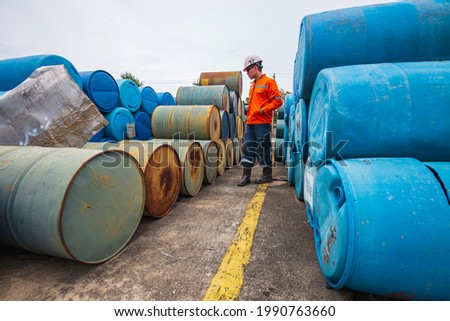 Male worker inspection record old drum oil stock barrels blue and green horizontal or chemical for in the industry.