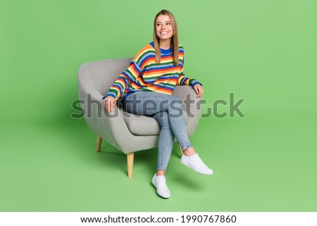 Full length body size photo smiling girl sitting in grey chair looking copyspace isolated pastel green color background Royalty-Free Stock Photo #1990767860