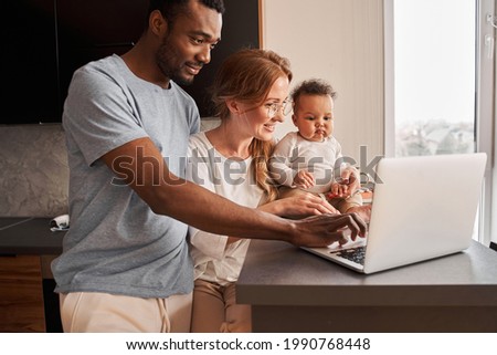 Family looking at the laptop screen while their child sitting