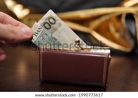 a photo showing a hand pulling PLN 100 from the wallet.