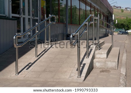 Shiny steel handrails at the entrance to the store. Handrails and ramp for disabled people. Royalty-Free Stock Photo #1990793333