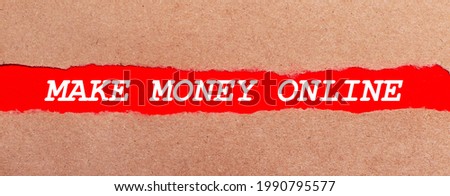 A strip of red paper under the torn brown paper. White lettering on red paper MAKE MONEY ONLINE. View from above