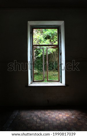Open window in an abandoned house overlooking the garden. Signs of destruction. Old building. Window frames without glass. Photos without people.Vertical photo.