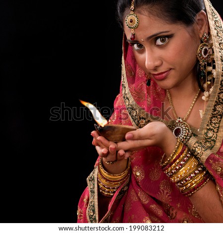 Beautiful Indian girl hands holding diya oil lamp, celebrating diwali festive of lights, traditional sari prayer isolated on black background with copy space on side.