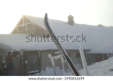 Ski in front of snowy cabin