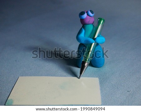 Funny frog writing on white card board with green pen, Text space cartoon clay image