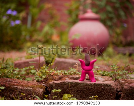 Red color cartoon man standing upon bricks around garden made with clay art