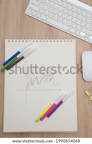 Drawing a graph of growth in a notebook on your desk at home.Wooden work table