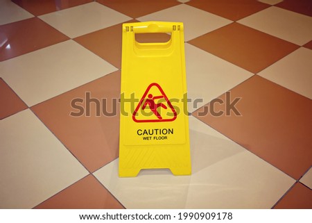 Yellow sign with the words Caution Wet Floor on tiled floor. The concept of cleaning, cleaning service, hotel, security measures. Sign showing warning of caution wet floor 

