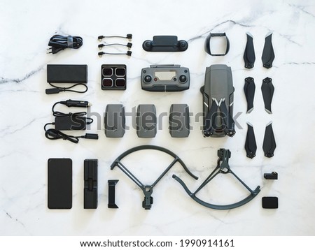 Set of folding drone or quadcopter with many accessories, top view or flat lay. Kit of folding drone and equipment for UAV over white marble background. Creative layout