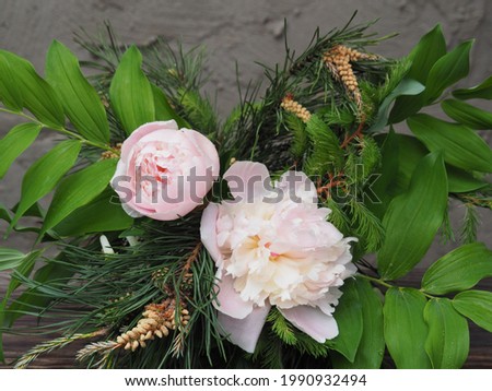 Delicate bouquet with branches of pine, spruce and white peony flowers on a gray background. Spring romantic picture with coniferous plants and flowers for invitation design, greeting card, wallpaper
