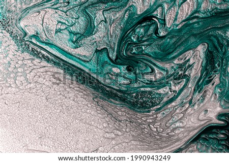 Beautiful shimmer turquoise and silver stains of liquid nail polish with bubbly texture,looks like ocean wave.Stripy paint texture.Nail lacquer flow modern backdrop. Minimalism concept.Copy space.