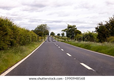 A British road seen from the driver or passenger view. The road open and free from other vehicles. Take during the summertime sunshine.