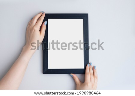 Hand Holding Blank white Photo Frame Hanging Wall for Design Mockup Template.