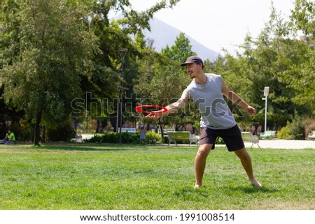 Young man playing with flying disc on sunny day at the park. Sports activity, recreation concepts