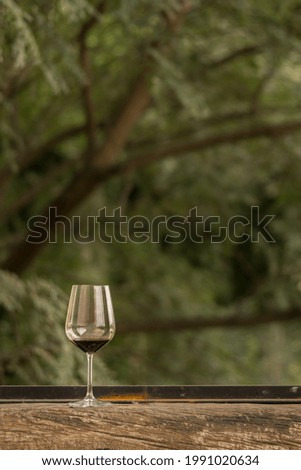 An almost empty glass of red wine put on a wooden window sill