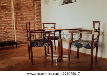the interior of a room with beautifully patterned wooden chairs, a table and a hanger